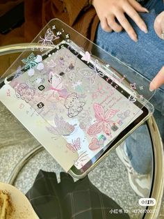 a person sitting on a glass table with a tablet in front of them and some butterflies