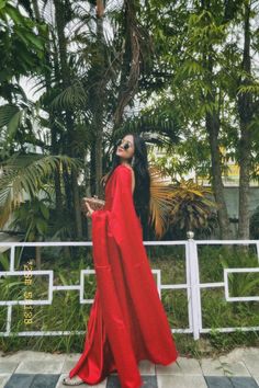 a woman in a red dress is standing outside