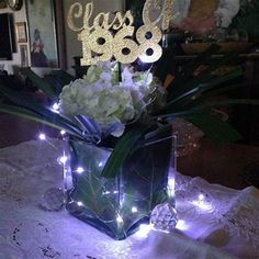 there is a vase with flowers and lights on the table in front of a mirror