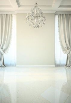 an empty room with chandelier and curtains