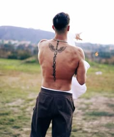 a man with a tattoo on his back holding a frisbee in the air