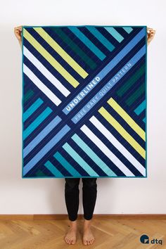 a person holding up a large blue and yellow quilt with the words, magnificently designed