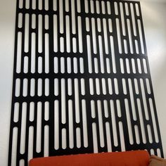 an orange couch sitting in front of a black grill on the wall next to a white wall