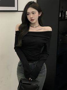 a woman is posing with her hand on her hip while wearing a black off the shoulder top