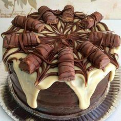 a chocolate cake with white icing and drizzled on top is sitting on a plate