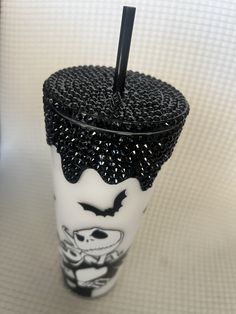 a black and white cup with a straw sticking out of it's top, sitting on a table