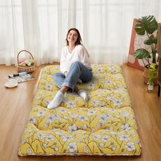 a woman sitting on top of a yellow flowered mattress