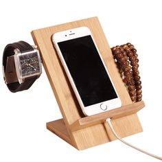 an iphone charging in a wooden stand with beads and a watch on the wrist strap