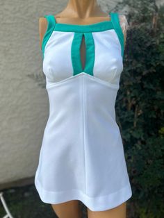 Here is a vintage 1970s tennis dress. Made by Court One . Size 5/6. Bust 32",waist 28", hips,36", length from top of shoulder to hem 28". Zips up the back. White polyester fabric. Green straps and middle bodice. Nice vintage condition Fitted Sleeveless Tennis Tops, Fitted Tennis Tops, Fitted Tennis Tops For Summer, White Fitted Tennis Top, Fitted Sleeveless Tennis Dress, Sleeveless Tennis Mini Dress For Spring, Sleeveless Mini Tennis Dress For Spring, Fitted White Tennis Dress, Fitted Sleeveless Tennis Mini Dress