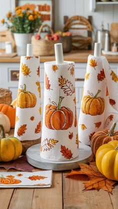 three pumpkins and leaves are on the table next to some napkins that have been folded