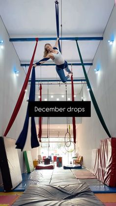 a woman is doing aerial acrobatics in an indoor gym