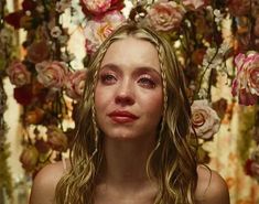 a woman with long hair standing in front of flowers