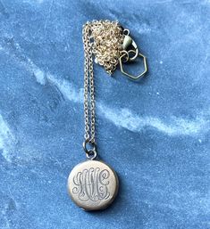 "This necklace was handmade using a combination of new and antique materials. It features an antique small round gold-filled locket that has one blank side and one side engraved with the initials MMcG. It is on a new gold-filled chain that is finished with an antiqued brass (over copper) lobster clasp and a brass hexagon loop. The locket measures .75\" tall and .75\" across. The chain is 18\" long. Condition: Minor surface scuffs consistent with age." Gold Medallion Necklaces With Engraving Option, Heirloom Jewelry With Engraving Option, Yellow Gold Medallion Necklaces With Engraving Option, Yellow Gold Medallion Necklace With Engraving Option, Victorian 14k Gold Jewelry With Engraving Option, Antique Jewelry With Engraving Option For Anniversary, Antique Yellow Gold Jewelry With Engraving Option, Gold Charm Necklaces With Engraving Option, Classic Wedding Necklaces With Engraving Option