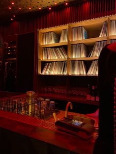 a bar with lots of records on the shelves and glasses in front of it at night