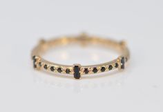 a yellow gold ring with black and white diamonds on the sides, sitting on a white surface