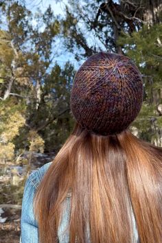 the back of a woman's head with long red hair and a knitted hat on her head