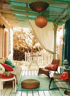 an outdoor covered porch with wicker furniture and blue drapes on the side wall