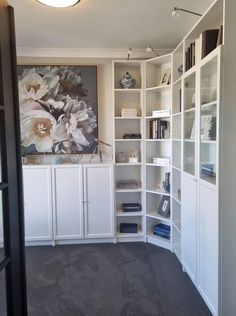 an empty room with white bookcases and flowers on the wall