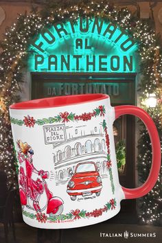 a red and white coffee mug sitting on top of a table next to a christmas tree