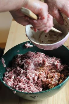 someone mixing food in a bowl on top of a wooden table