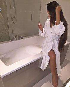 a woman taking a selfie in front of a bathtub with her legs crossed