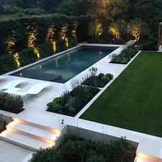 an aerial view of a modern garden and pool area at night with lights on the grass