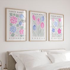 three framed art prints on the wall above a bed with white linens and pillows