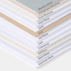 a stack of white and beige sheets stacked on top of each other in different sizes