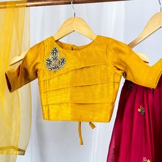 Dress your little one in this stunning yellow and red silk lehenga choli set. The choli top features cut-out sleeves, and the lehenga choli is adorned with intricate computer embroidery work. The set comes with a matching yellow dupatta and is lined with soft butter crepe, ensuring your child's comfort. Buy now and let your little fashionista steal the show! Please Note: Color of the actual product may vary slightly from the image(s) shown. Yellow Embroidered Raw Silk Dress, Yellow Sets With Unstitched Blouse For Puja, Yellow Set With Unstitched Blouse For Puja, Festive Yellow Blouse With Gota Work, Yellow Festive Top For Eid, Yellow Raw Silk Sets For Puja, Yellow Raw Silk Choli With Gota Work, Yellow Raw Silk Set For Navratri, Yellow Embroidered Raw Silk Sets