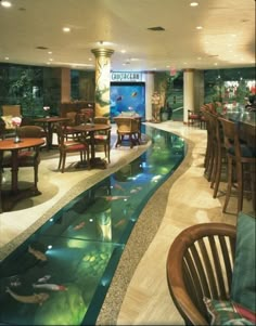 an indoor dining area with tables and chairs next to a small pool in the middle