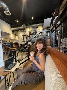 a woman sitting on the floor holding a coffee cup