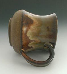 a brown and white ceramic object with a ring on it's end, sitting on a table