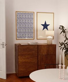 a living room with a table and two pictures on the wall