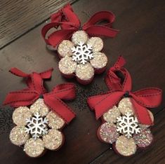 three christmas ornaments with bows and snowflakes hanging from them on a wooden table