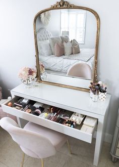 a white desk with a mirror on it and some pink chairs in front of it