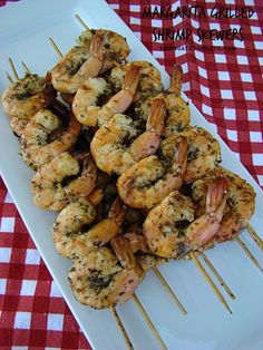 grilled shrimp skewers on a white plate with red and white checkered tablecloth