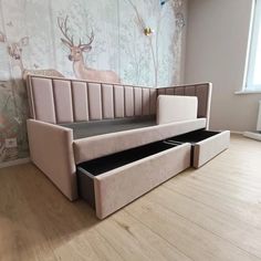 a couch with two drawers in front of a wallpapered wall and wooden floor