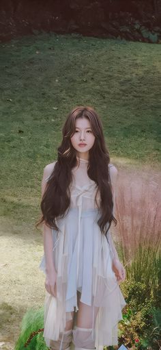 a woman standing in the grass with long hair