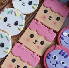 some decorated cookies are laying on a wooden table and one has a cat in the middle