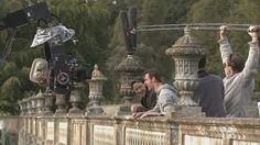 three men on a bridge holding up their cameras and video equipment to take pictures with them