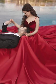 a woman in a red dress laying on the ground next to a man in a black suit