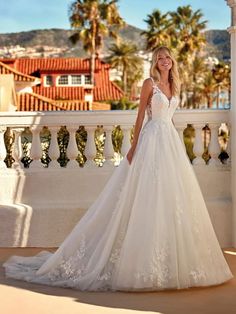 a woman in a wedding dress standing on a balcony with palm trees and buildings behind her