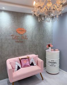 a pink couch sitting in front of a chandelier next to a white barrel