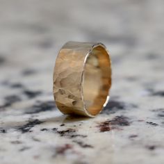 a gold ring sitting on top of a marble counter next to a black and white speckled wall