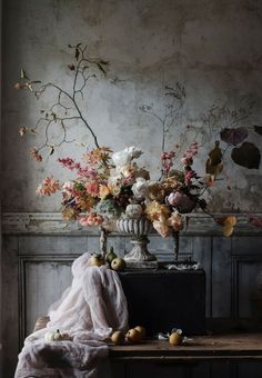 a vase filled with flowers sitting on top of a wooden table next to a wall