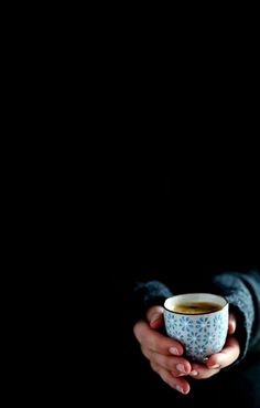 a woman holding a cup of coffee in her hands, against a black background photo