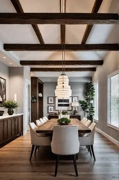 a large dining room table with white chairs and wooden beams in the ceiling above it