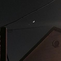 the moon and venus are visible in the night sky over a building with power lines