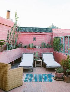 an outdoor patio with two lounge chairs and potted cacti on the side