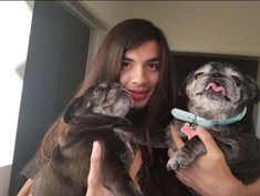 a woman holding two dogs in her hands and pointing to the camera with one hand